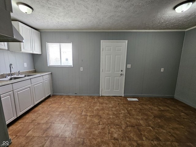 kitchen with crown molding, baseboards, light countertops, white cabinets, and a sink