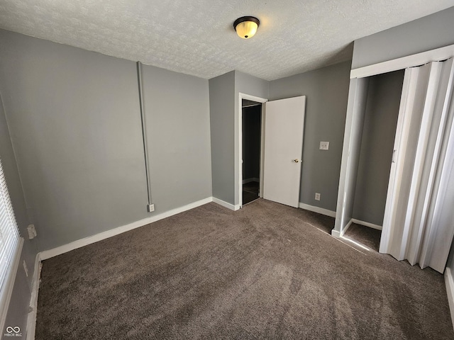 unfurnished bedroom with a closet, baseboards, a textured ceiling, and dark carpet