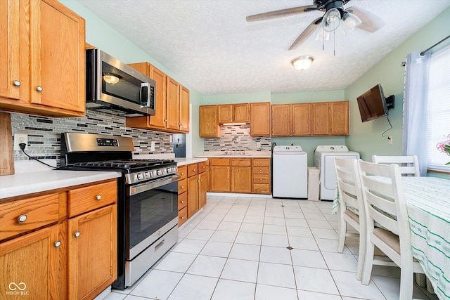 kitchen featuring backsplash, washing machine and dryer, light countertops, brown cabinetry, and stainless steel appliances