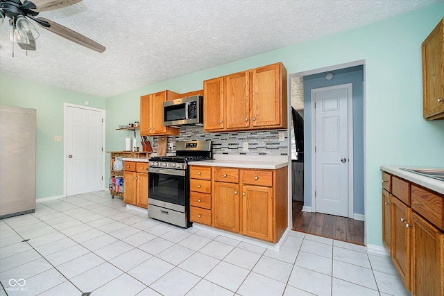 kitchen with stainless steel appliances, backsplash, brown cabinetry, and light countertops