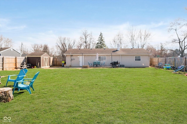 rear view of house featuring an outbuilding, a fenced backyard, a lawn, and a shed