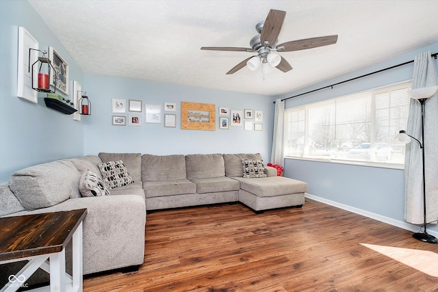 living room with ceiling fan, baseboards, and wood finished floors