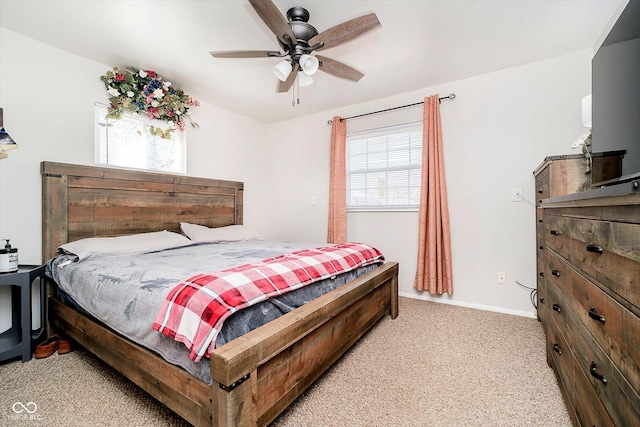 bedroom with light carpet, multiple windows, a ceiling fan, and baseboards