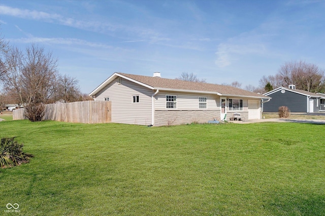 back of property with a garage, fence, and a lawn