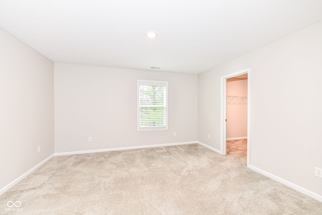 unfurnished room featuring baseboards and light carpet