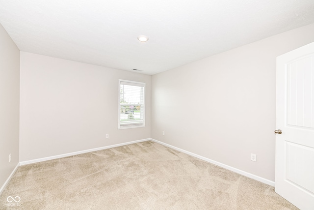 spare room featuring baseboards, light carpet, and visible vents