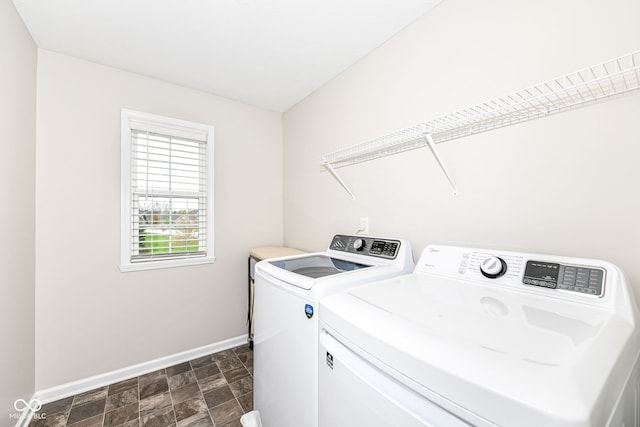 clothes washing area with stone finish floor, laundry area, washing machine and dryer, and baseboards