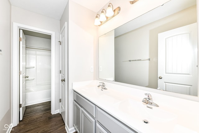 full bathroom with a sink, wood finished floors, double vanity, and a bath