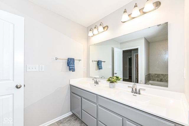 full bath with double vanity, baseboards, and a sink