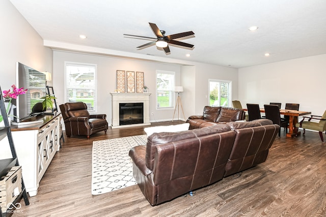 living room featuring recessed lighting, a glass covered fireplace, and wood finished floors