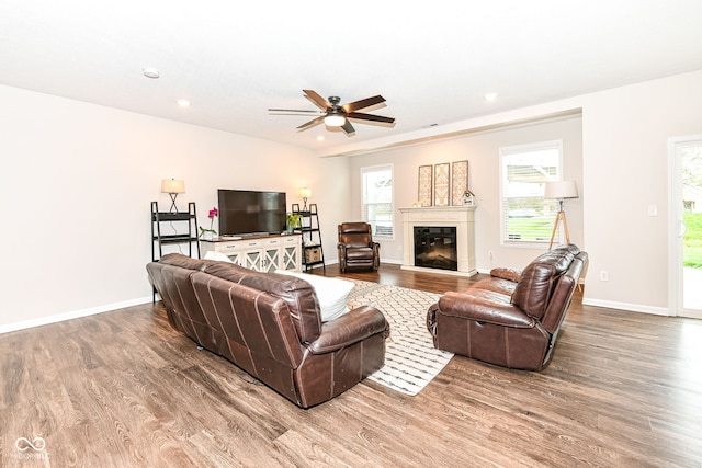 living room featuring a glass covered fireplace, baseboards, wood finished floors, and recessed lighting