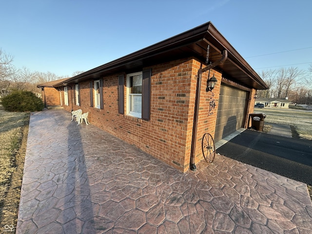 view of home's exterior featuring aphalt driveway, a garage, and brick siding