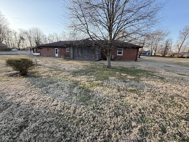 view of side of property with brick siding, crawl space, and a yard