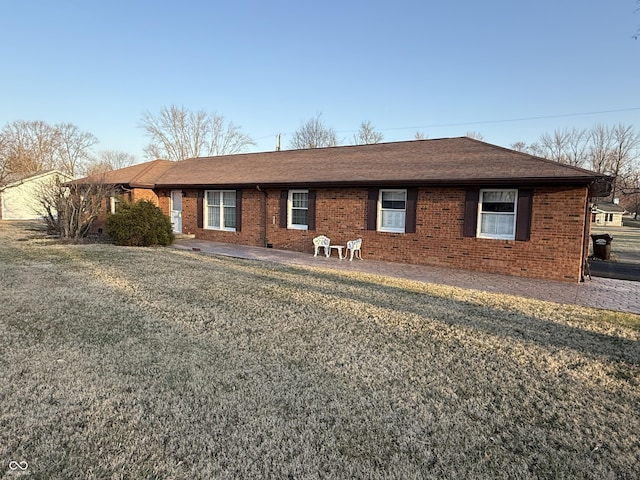 ranch-style house with brick siding, a front lawn, and a shingled roof