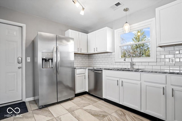 kitchen featuring a sink, appliances with stainless steel finishes, dark stone countertops, and white cabinetry