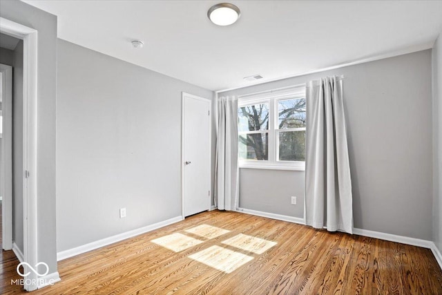 spare room with visible vents, baseboards, and wood finished floors