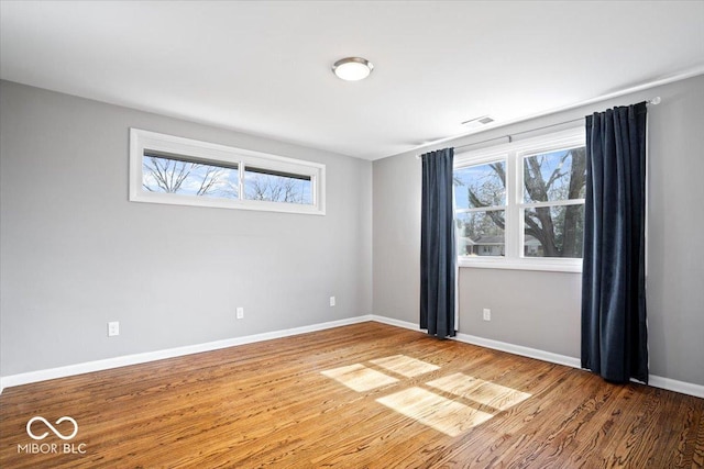 empty room featuring visible vents, baseboards, and wood finished floors