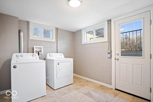 washroom featuring baseboards, washing machine and dryer, and laundry area