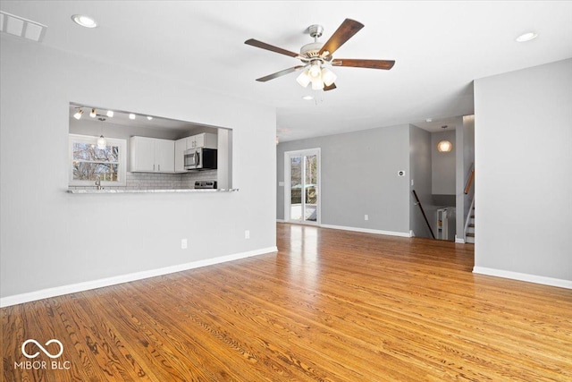 unfurnished living room with visible vents, stairway, baseboards, and light wood-style floors