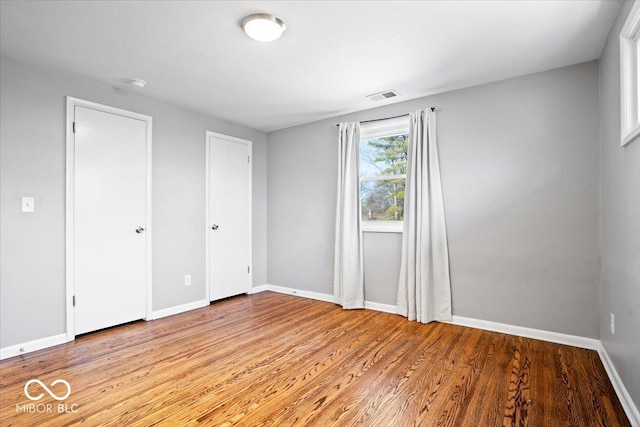 unfurnished bedroom featuring light wood finished floors, visible vents, and baseboards