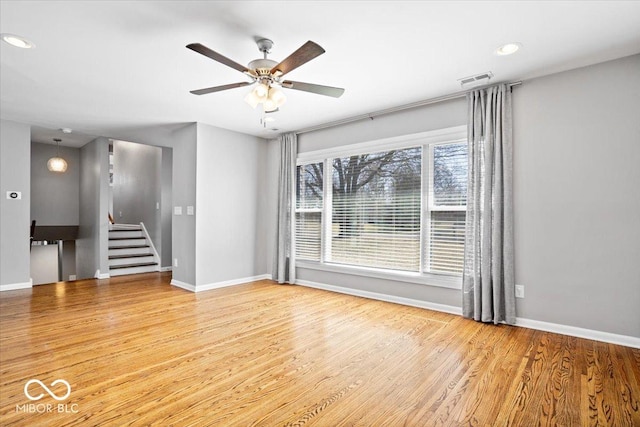 empty room featuring stairway, wood finished floors, and baseboards