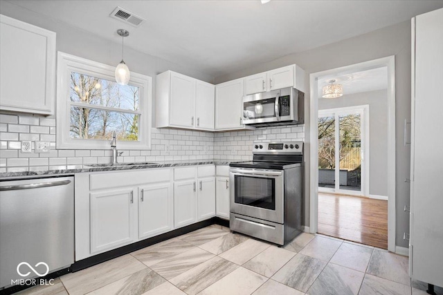 kitchen featuring dark stone countertops, visible vents, a sink, stainless steel appliances, and white cabinets