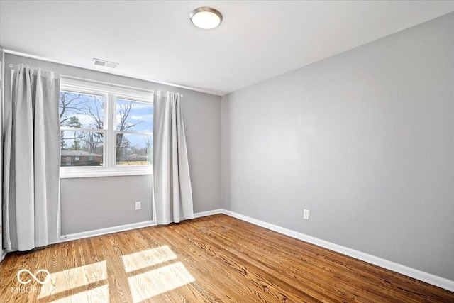 empty room featuring visible vents, baseboards, and wood finished floors