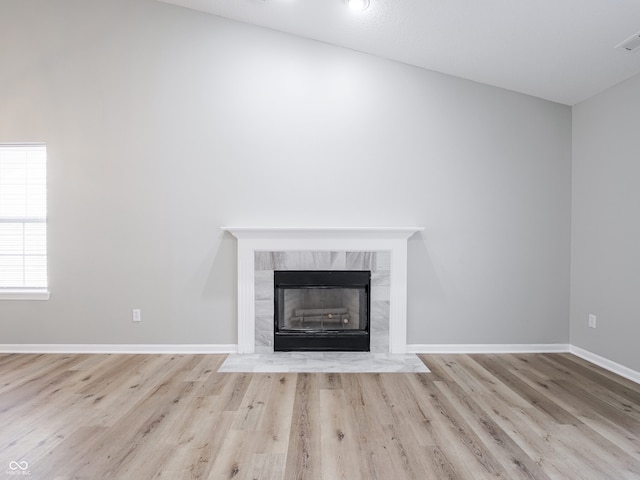 unfurnished living room with baseboards, wood finished floors, and a tile fireplace