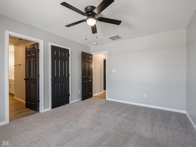 unfurnished bedroom with carpet flooring, baseboards, visible vents, and a textured ceiling