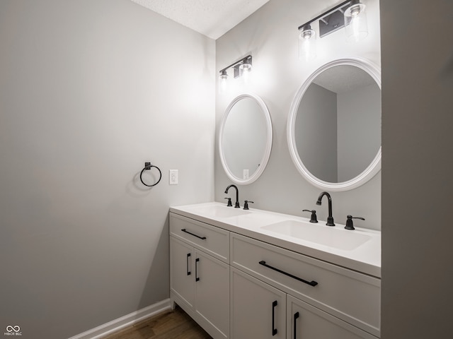 bathroom featuring a sink, baseboards, wood finished floors, and double vanity