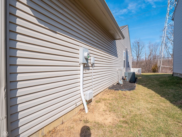 view of side of home with central AC unit and a lawn