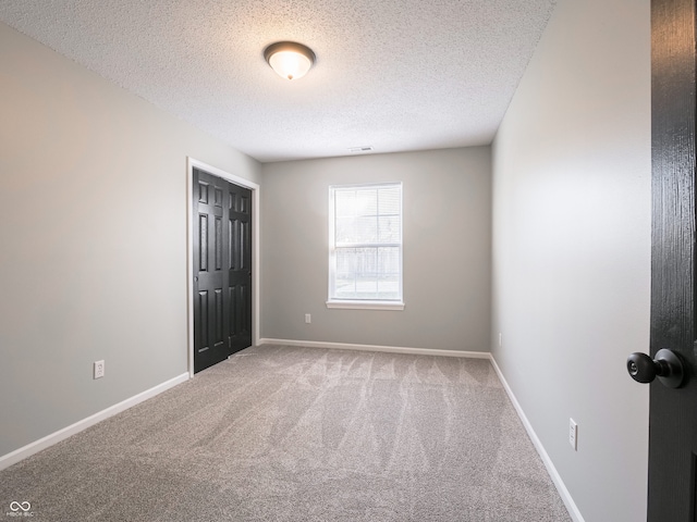 carpeted empty room with visible vents, baseboards, and a textured ceiling