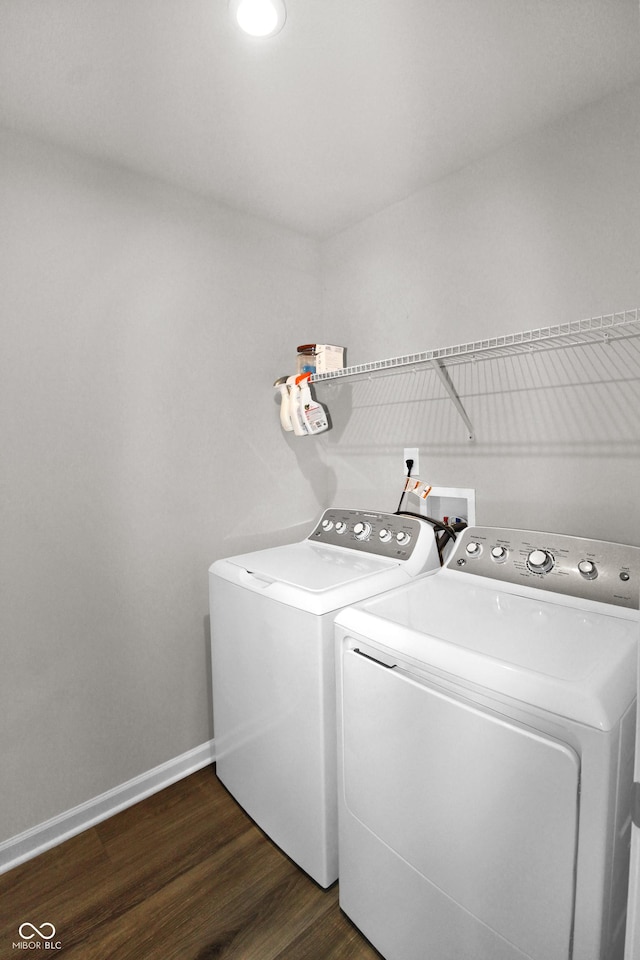 clothes washing area featuring laundry area, baseboards, dark wood-style flooring, and washing machine and clothes dryer