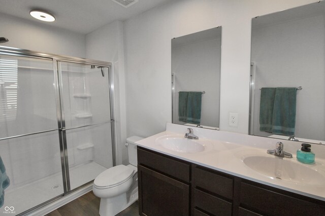 bathroom with a sink, toilet, a stall shower, and double vanity