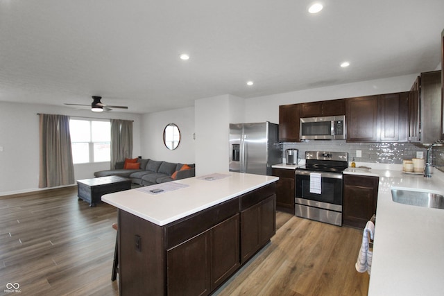 kitchen featuring decorative backsplash, wood finished floors, a kitchen island, and stainless steel appliances