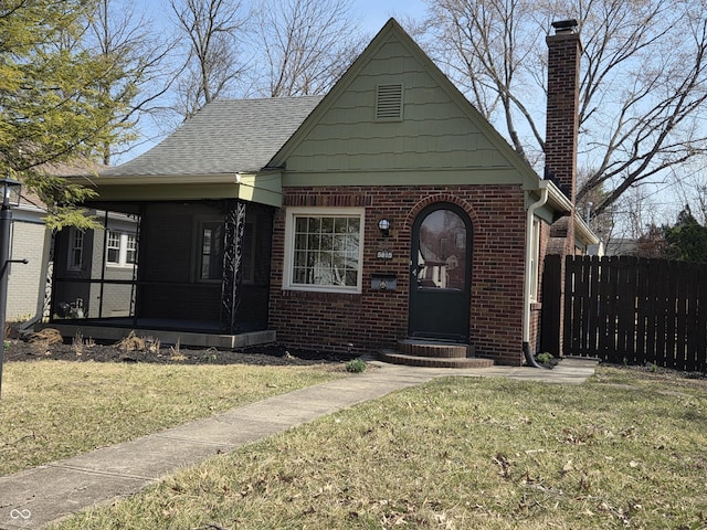 view of front facade featuring brick siding, a front lawn, fence, entry steps, and covered porch