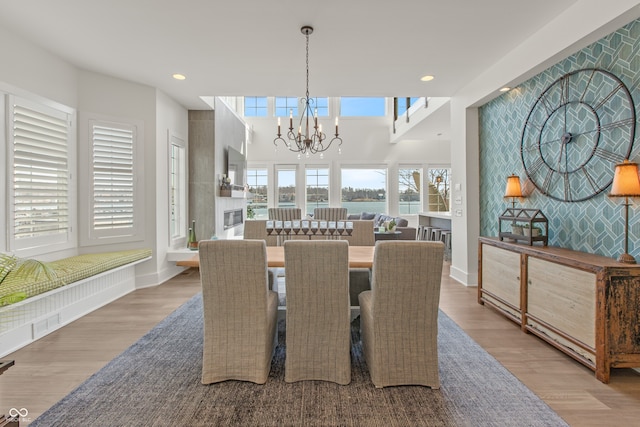 dining area featuring wood finished floors, baseboards, recessed lighting, an accent wall, and a notable chandelier