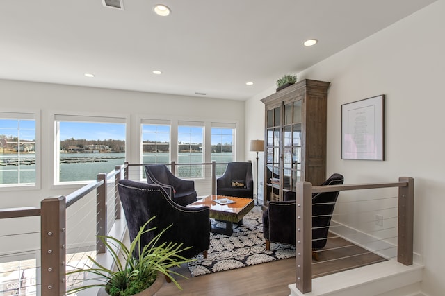 living area featuring recessed lighting, visible vents, a water view, and wood finished floors