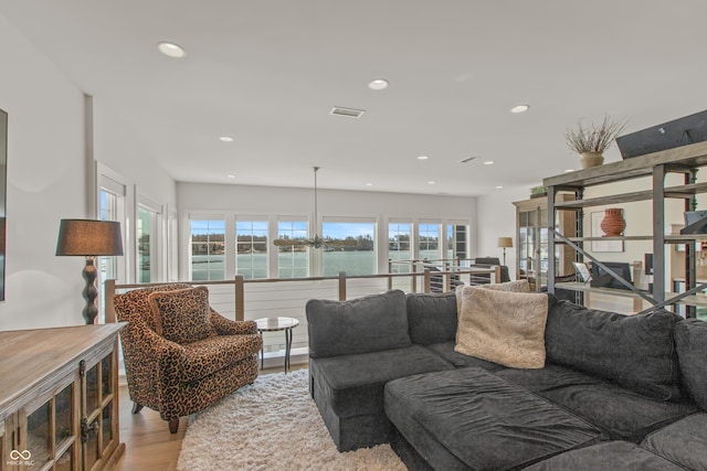 living area featuring recessed lighting, light wood-type flooring, a water view, and visible vents