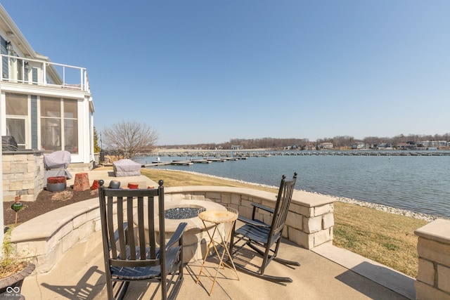 view of patio featuring an outdoor fire pit, a balcony, and a water view