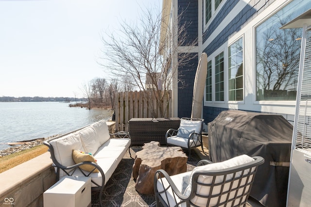 view of patio featuring grilling area, an outdoor hangout area, fence, and a water view