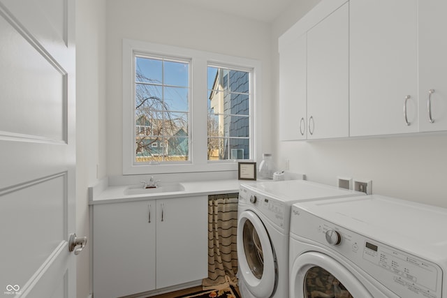 laundry room with cabinet space, washer and dryer, and a sink