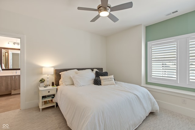 bedroom featuring light colored carpet, visible vents, ensuite bathroom, and baseboards