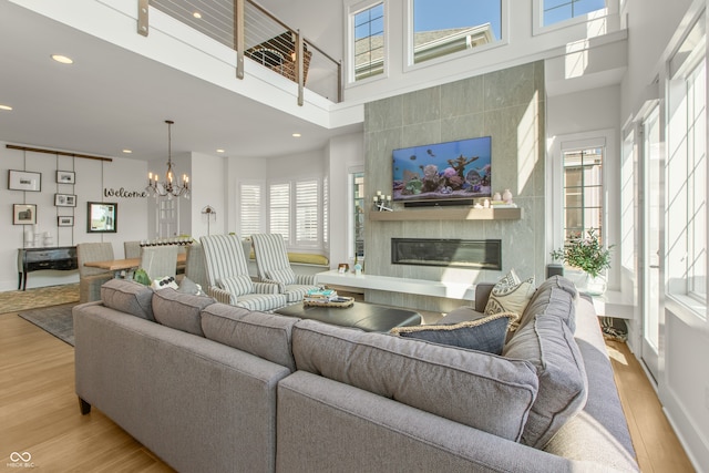 living area with a notable chandelier, recessed lighting, a tile fireplace, and light wood-type flooring