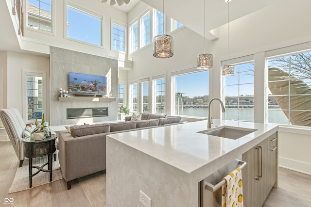 kitchen with light stone counters, a sink, light wood-style floors, pendant lighting, and modern cabinets