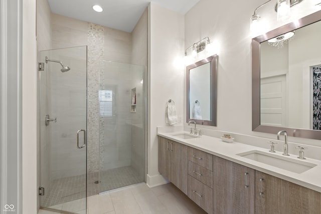 bathroom featuring double vanity, a stall shower, and a sink