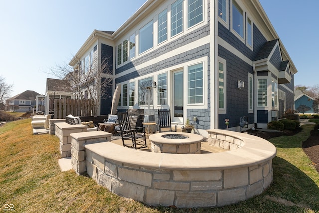 rear view of property featuring a yard, fence, and an outdoor fire pit