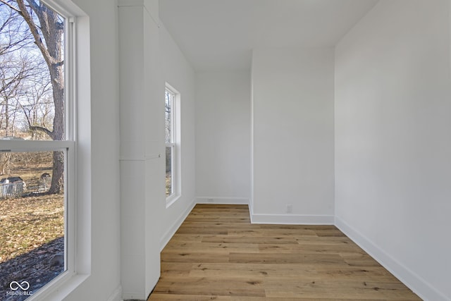 spare room featuring plenty of natural light, wood finished floors, and baseboards