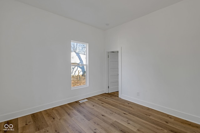 empty room featuring visible vents, baseboards, and wood finished floors