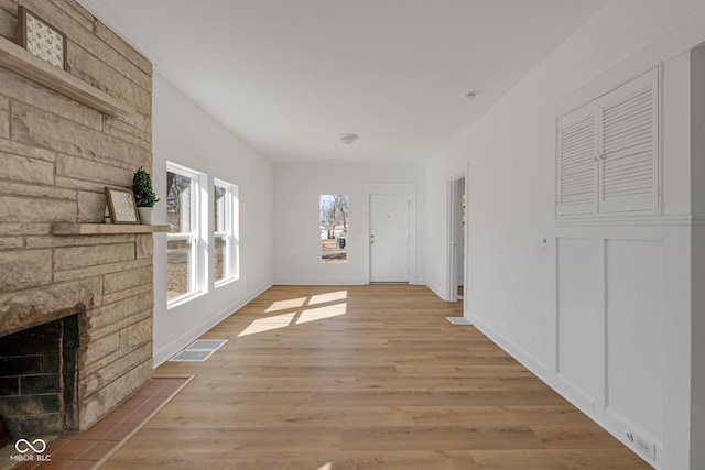 hallway with light wood-type flooring, visible vents, and baseboards